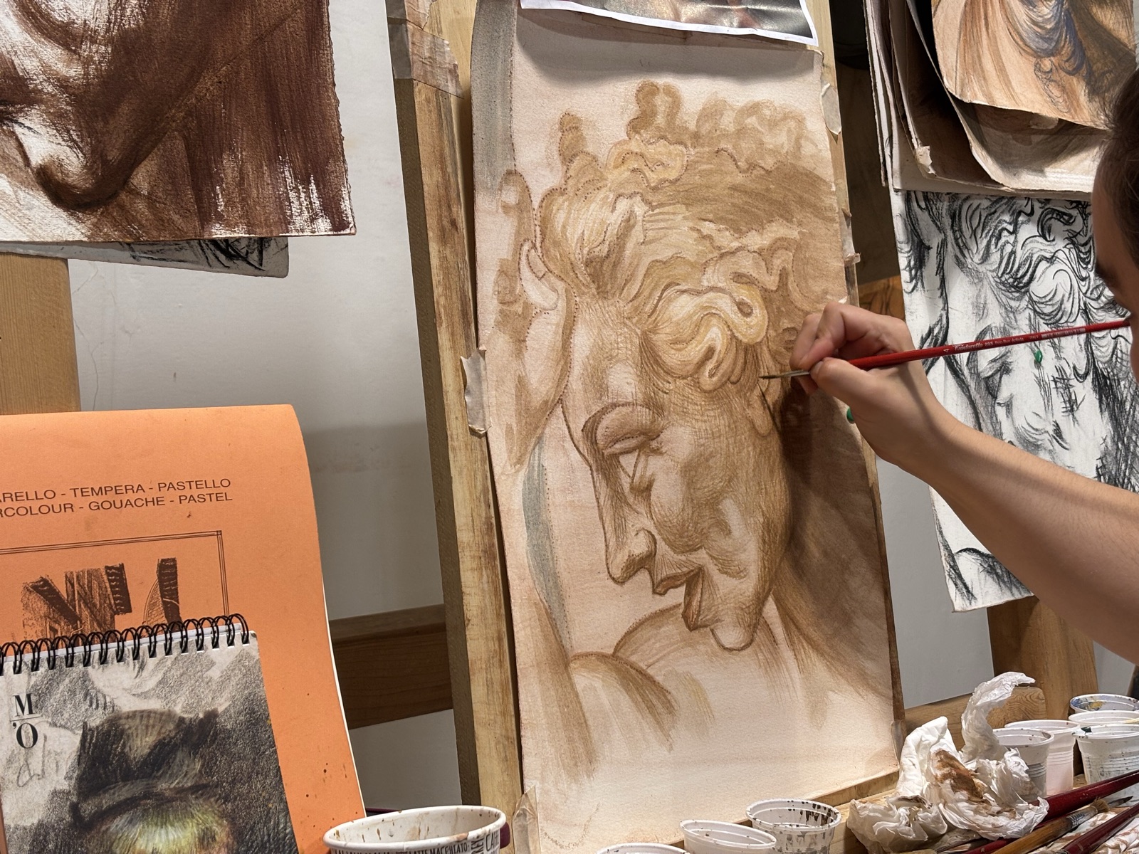 Una mano con il pennello su uno studio di testa